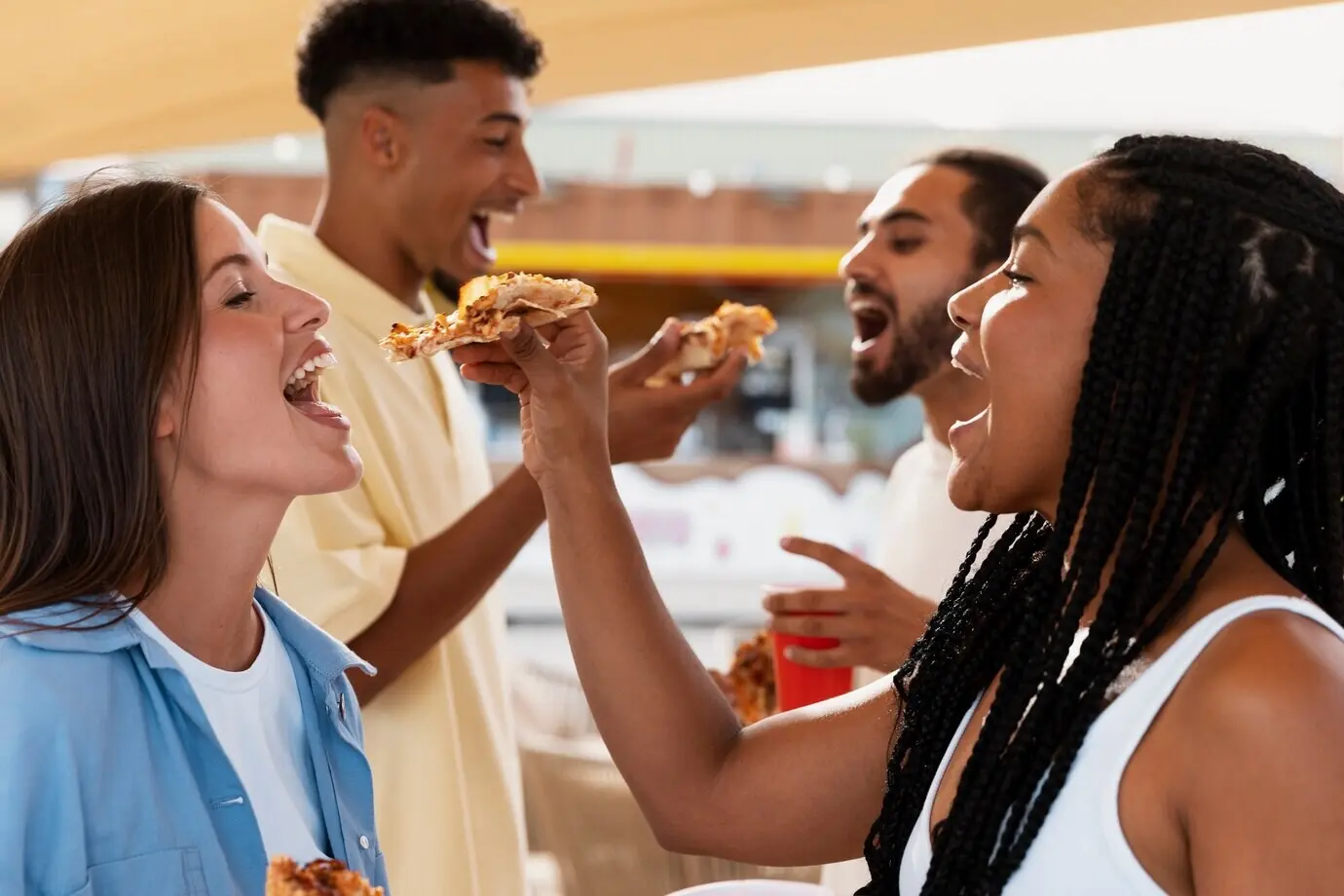 People eating pizza seen from the side.